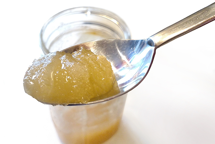spoonful of crystallized honey with jar in background